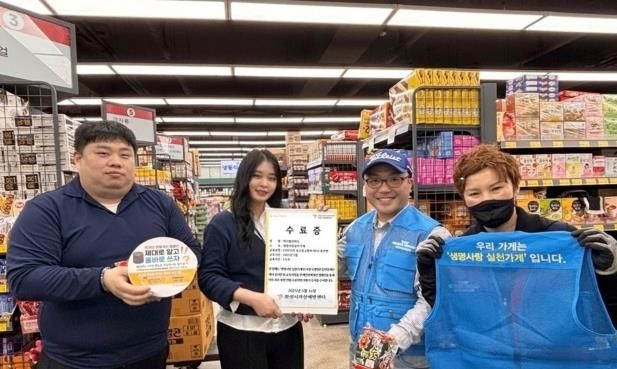 화성특례시 자살예방센터가 운영하는 ‘생명사랑 실천가게’ 캠페인에 참여 중인 진안동 ‘럭키할인마트’ 관계자들이 번개탄 올바른 사용 안내물과 생명사랑 문구가 새겨진 조끼 등을 들고 기념촬영을 하고 있다