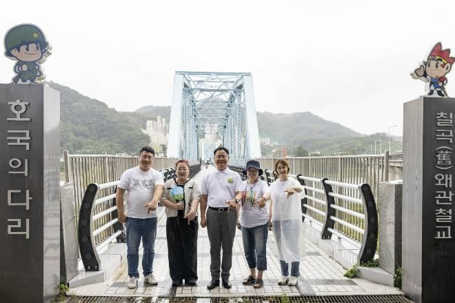 왜관읍문화도시사업추진단 임원진과 김재욱 칠곡군수가 호국의다리 앞에서 기념 촬영을 하고 있다. 이들은 120년의 세월을 품은 다리 위에, 지역 주민들의 기억을 모아 사진전 ‘120년의 추억 나들이’를 함께 준비했다.