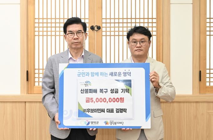 ㈜우보이엔씨 김경락 대표가 김광열 영덕군수에게 성금을 전달하고 있다.