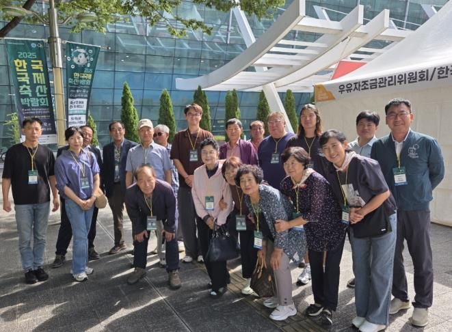밀양시낙농육우협회 회원들이 국제축산박람회장 입구에서 단체 기념 촬영을 하고 있다.