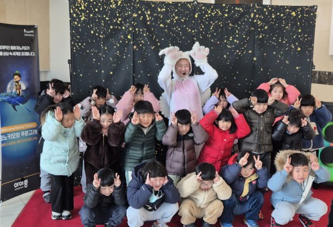 아이들이 공연 출연자와 함께 기념촬영을 하고 있다.