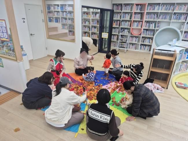 북스타트 부모교육 프로그램에 참여한 영·유아와 양육자가 낙엽놀이 활동을 하고 있다.